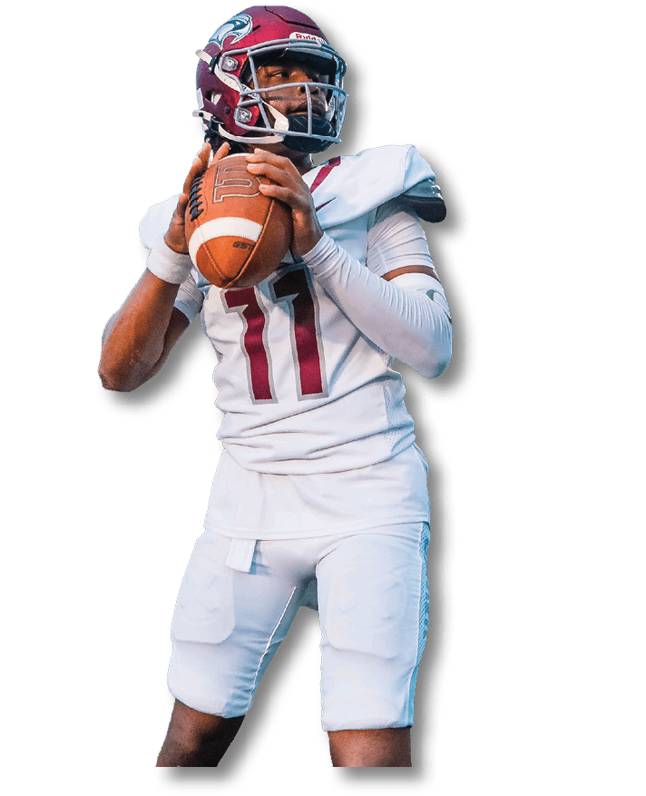 A person wearing a maroon football helmet and white uniform is holding a football in a ready-to-throw position. Description generated by AI