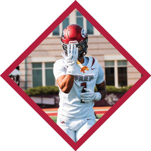 A person wearing a red football helmet and white uniform with the word “PREP" on the chest is standing on a football field with one hand raised to their face. Description generated by AI