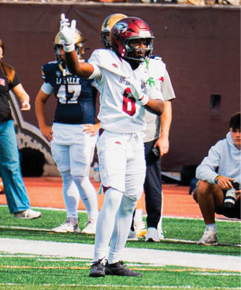 A person in a football uniform with the number 4 and the word “PREP" on the jersey is standing on a football field at night. Description generated by AI
