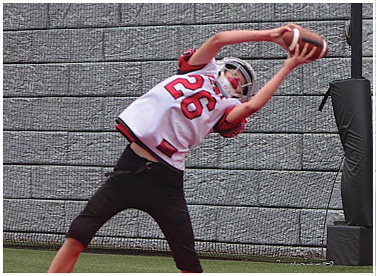 A football player catching a ball. Description generated by AI