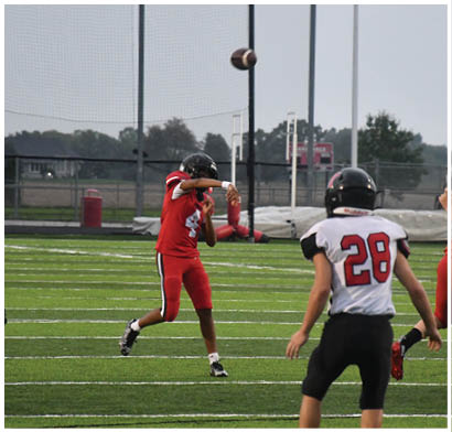 Two people in white and green football uniforms stand on a field with one clenching a fist and a referee and opposing players in red uniforms visible in the background. Description generated by AI