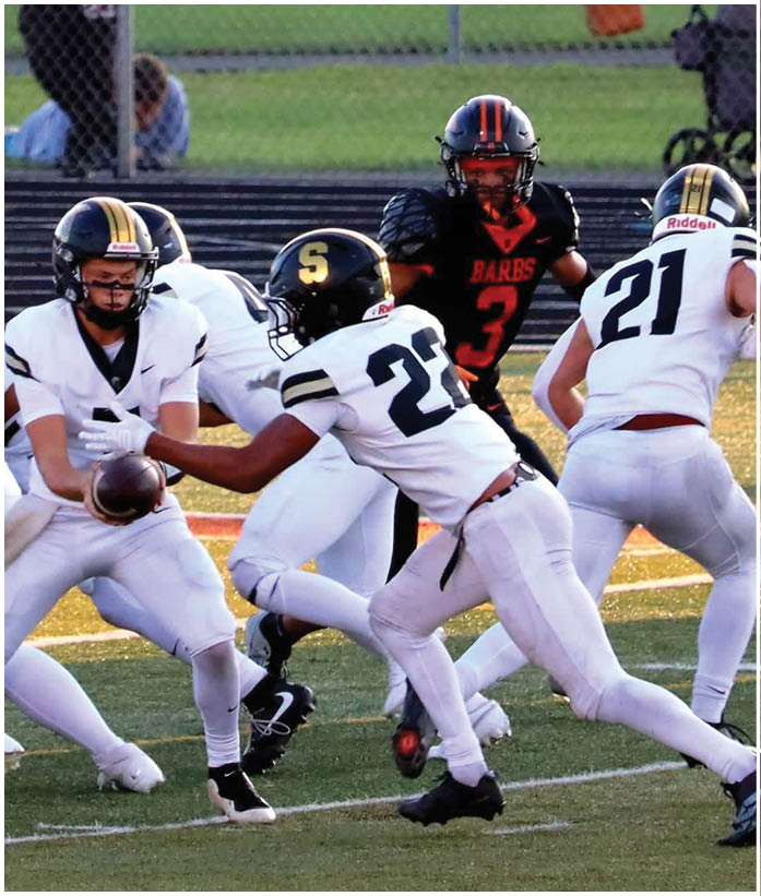 A group of football players wearing black and white uniforms. Description generated by AI