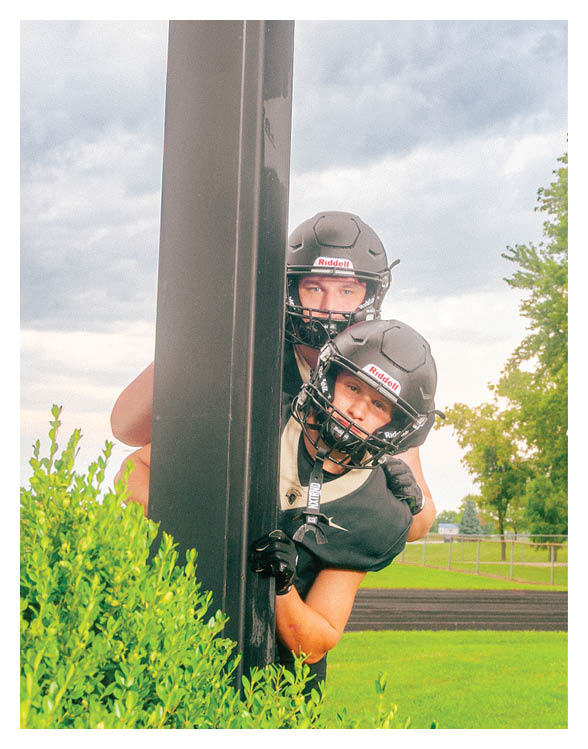 A football player wearing a helmet and white uniform is holding his helmet above his head. AI generated content