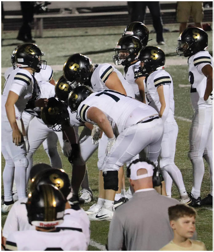 A group of football players wearing black and white uniforms. Description generated by AI