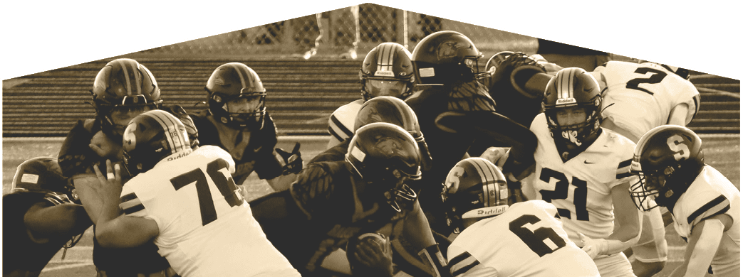 Several football players in helmets and uniforms are engaged in a close formation on the field during a game. Description generated by AI
