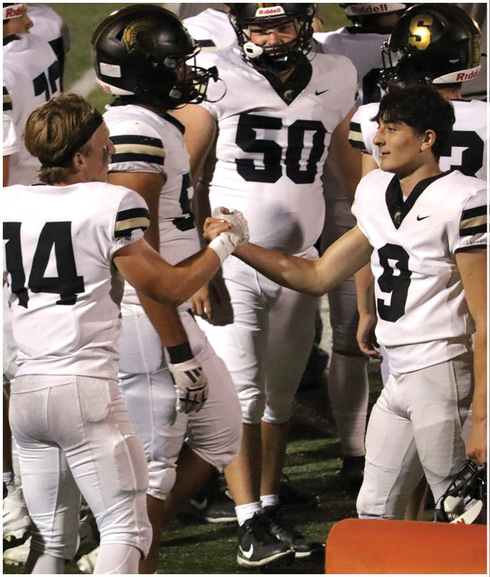 A group of football players wearing black and white uniforms. Description generated by AI