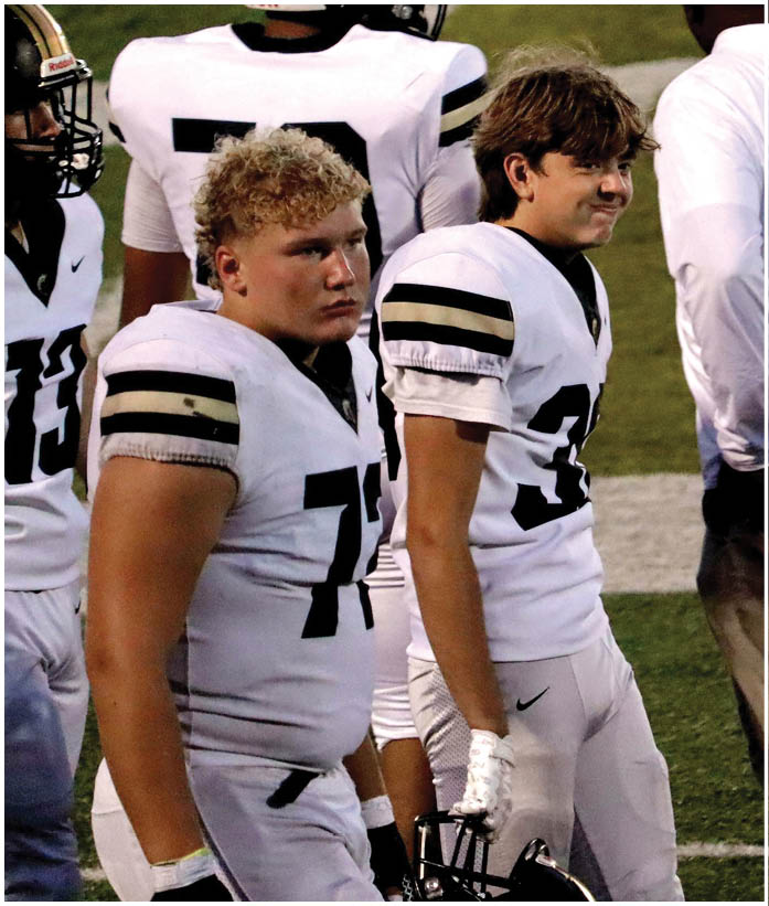 A group of football players wearing black and white uniforms. Description generated by AI