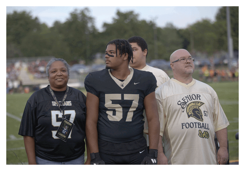 A group of football players on a field, one of them is running with a football. AI generated content