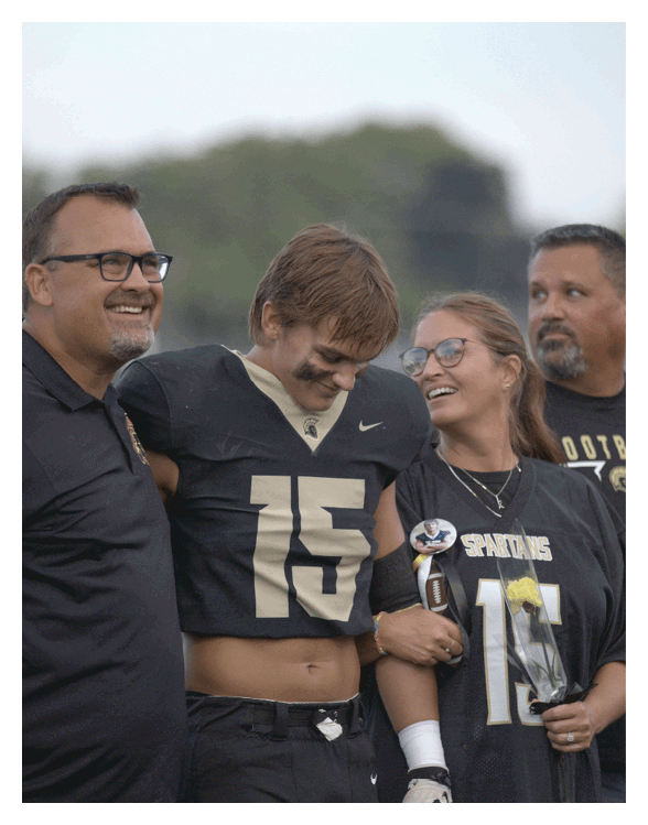 A football player wearing a helmet and white uniform is holding his helmet above his head. AI generated content