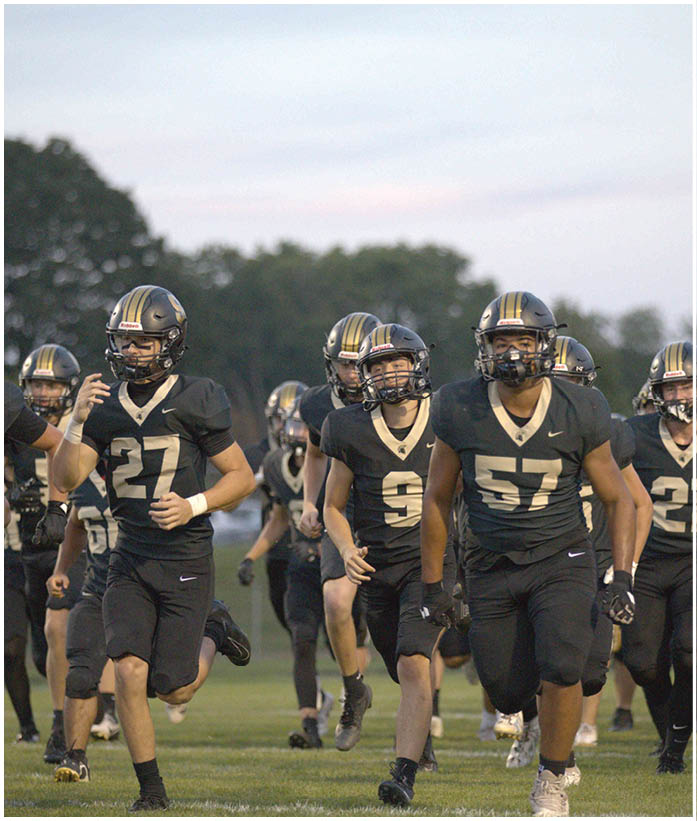A group of football players wearing black and white uniforms. Description generated by AI