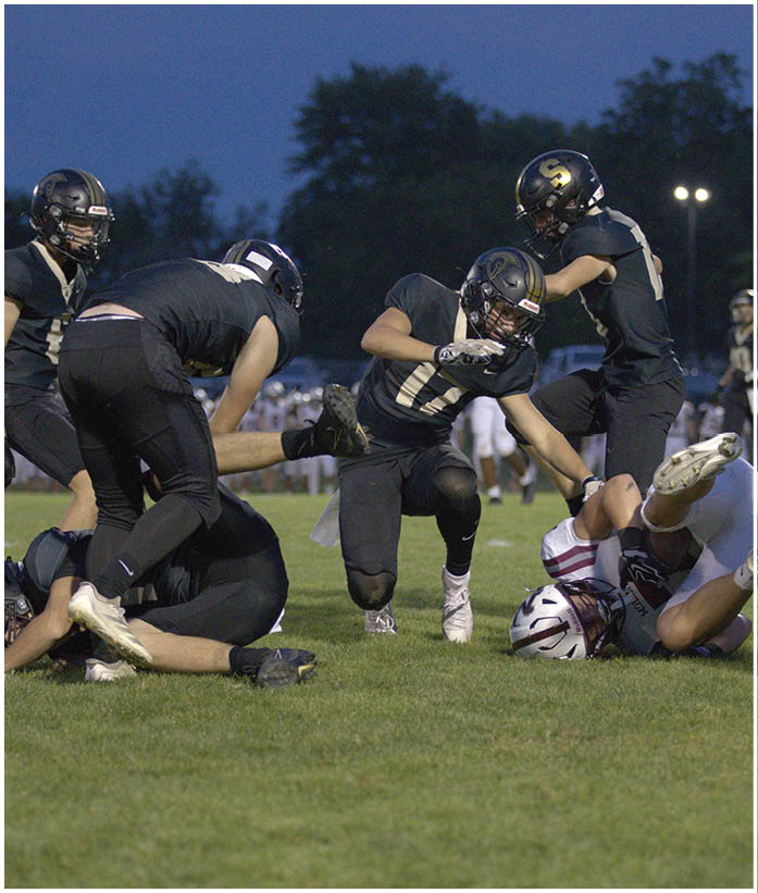 A group of football players wearing black and white uniforms. Description generated by AI