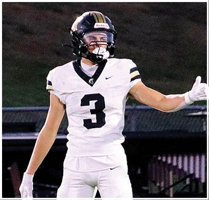A person wearing a football helmet and white jersey with the number three is giving a thumbs-up gesture on a field. Description generated by AI