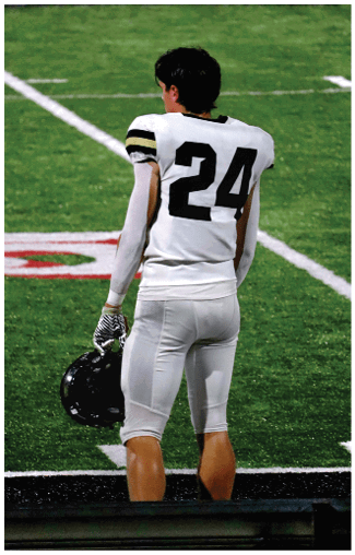 A person wearing a white sports jersey with the number 24 on the back stands on a grassy field. Description generated by AI