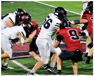 People wearing football uniforms are engaged in a play on a field with some players in red and black and others in white and black. Description generated by AI