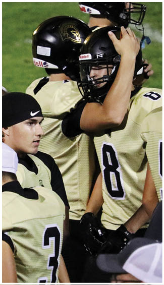 A person wearing a black Nike beanie and a sports jersey is looking to the side while surrounded by others in similar athletic attire. Description generated by AI