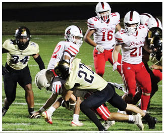 A group of people wearing football uniforms are engaged in a tackle on a grassy field during a game. Description generated by AI