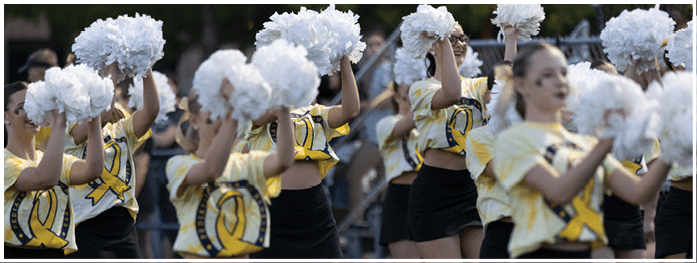 Three people wearing yellow tops and black skirts are standing close together, with the focus on their midsections. Description generated by AI
