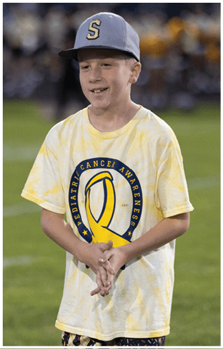 A person wearing a yellow tie-dye shirt is standing on a grassy field. Description generated by AI