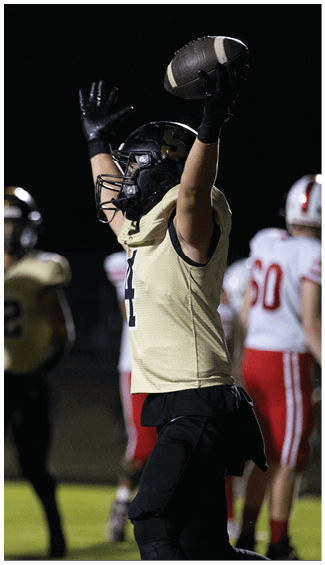 People wearing football uniforms and helmets are standing on a field at night. Description generated by AI