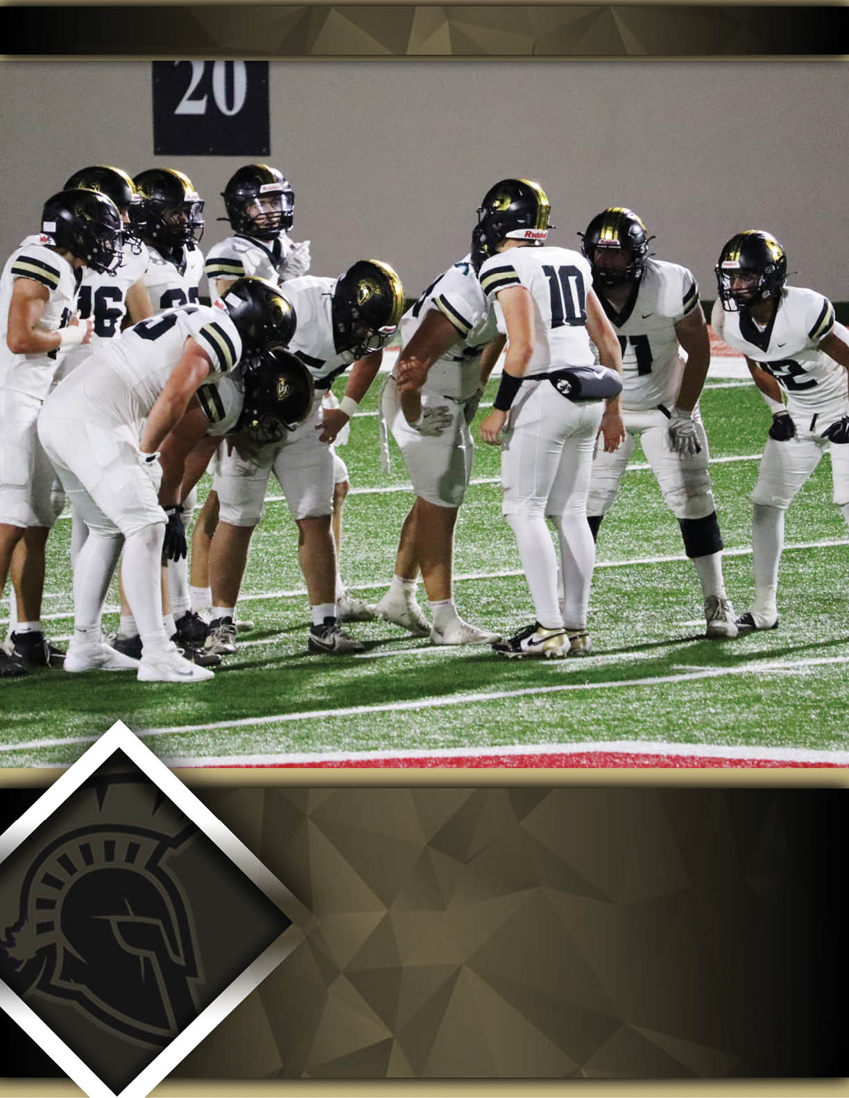 A group of football players in white uniforms and black helmets are huddled together on a field under stadium lights. Description generated by AI