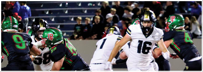 People in football uniforms are engaged in a play on the field with one person in white running and others in dark uniforms preparing to block or tackle. Description generated by AI