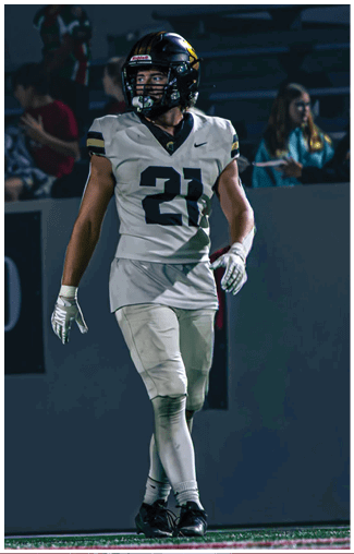 A person wearing light-colored pants with a visible seam is standing against a dark background. Description generated by AI