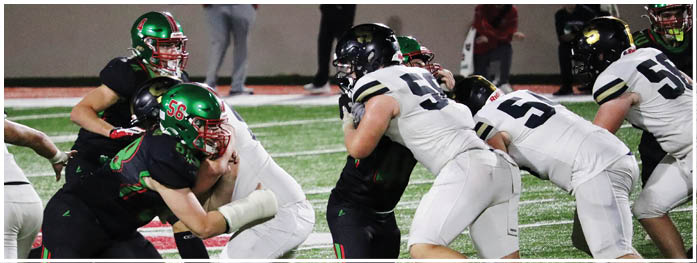 People in football uniforms are engaged in a play on a turf field with some players blocking and others attempting to tackle. Description generated by AI