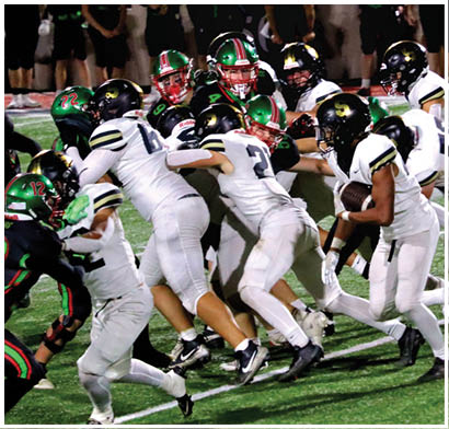 People in white football uniforms are actively running and tackling on a green field during a game. Description generated by AI