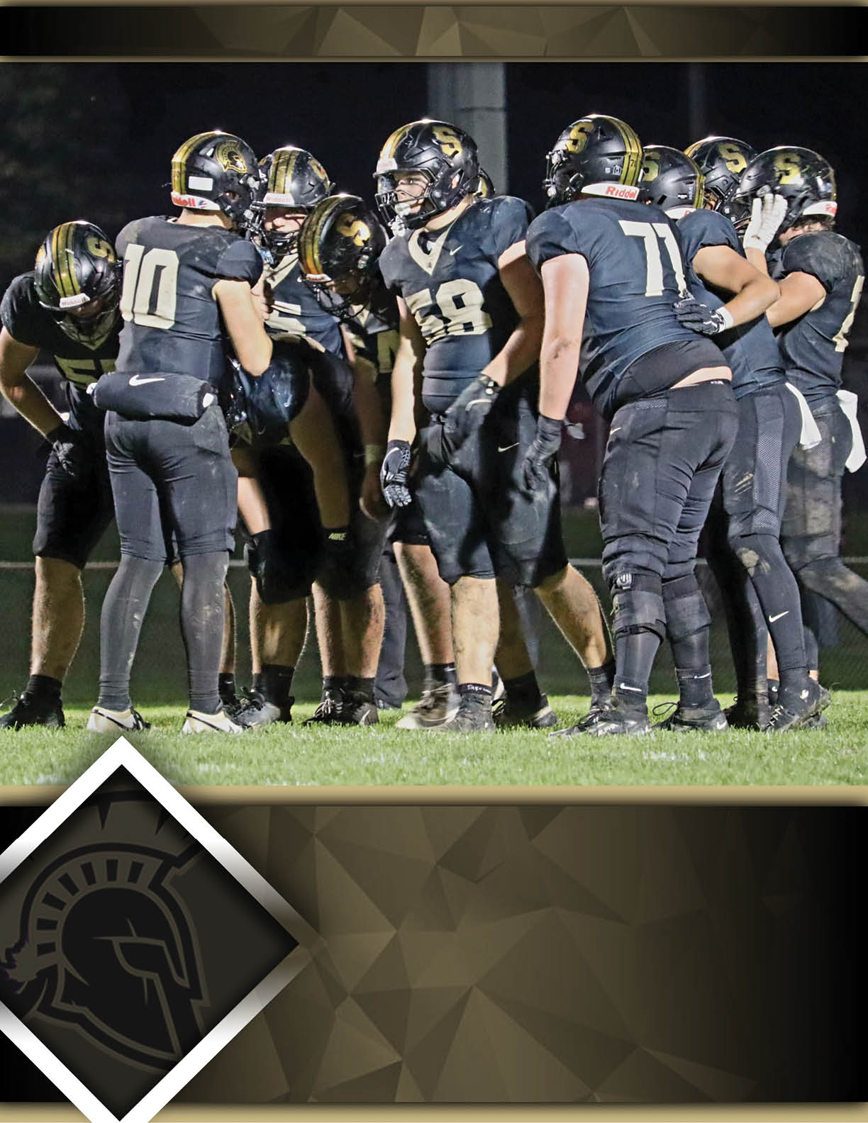 A group of people wearing black football uniforms and helmets are huddled together on a grassy field at night. Description generated by AI