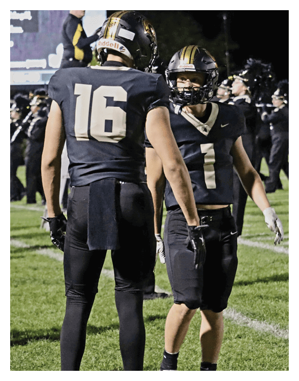 A football player wearing a helmet and white uniform is holding his helmet above his head. AI generated content