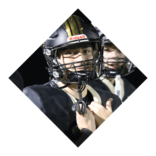 A football player wearing a black jersey with the number 10 sits on the ground with a football helmet on the ground next to him. AI generated content