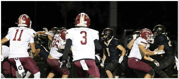 People wearing football uniforms are actively engaged in a nighttime game on the field. Description generated by AI