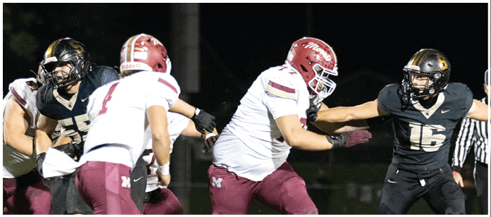 Two teams of football players in helmets and uniforms are engaged in a play on a nighttime field. Description generated by AI