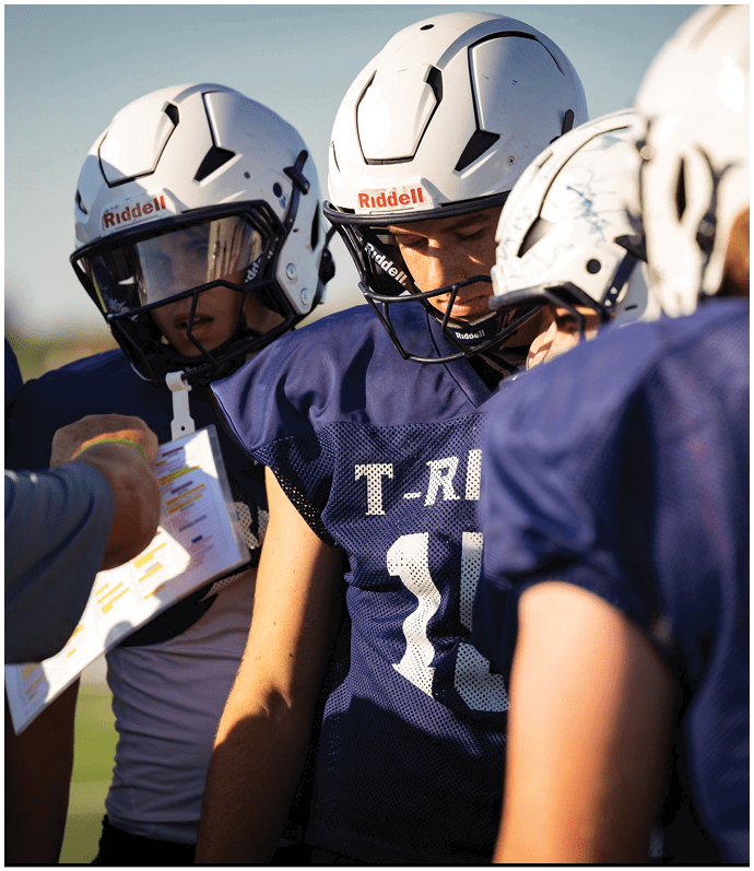 Three football players in blue and white uniforms running on a field. Description generated by AI
