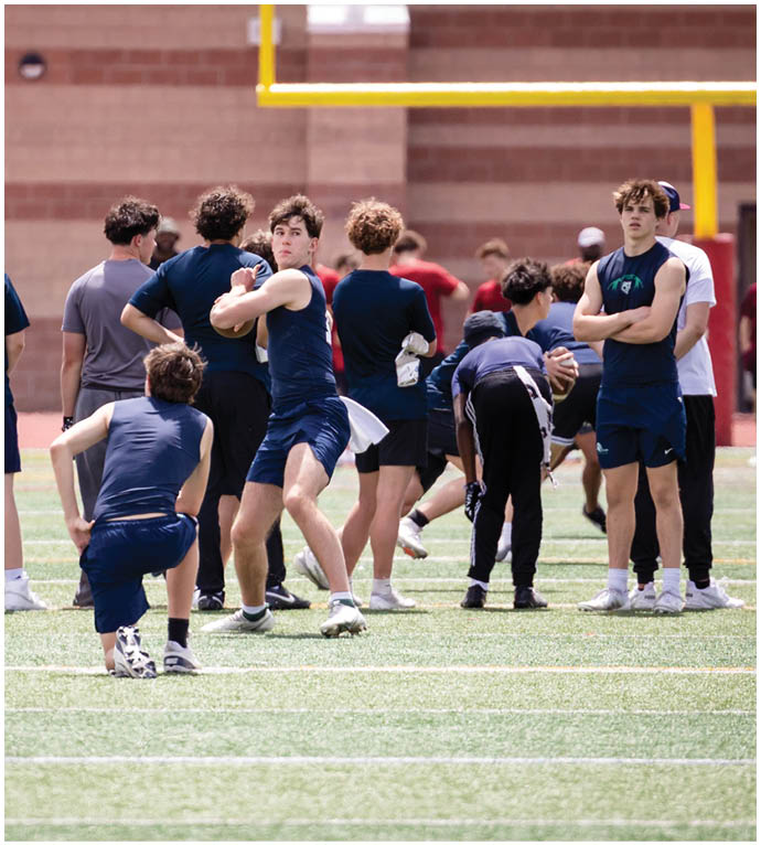 Three football players in blue and white uniforms running on a field. Description generated by AI