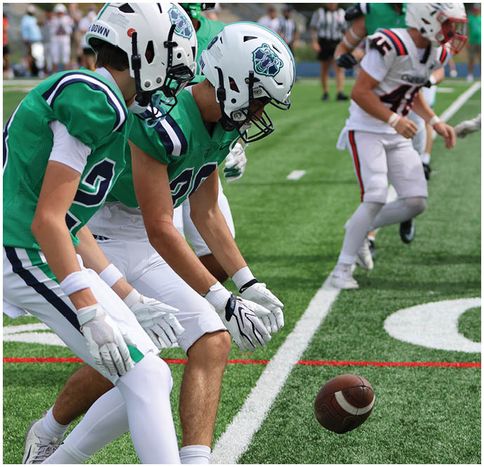 Three football players in blue and white uniforms running on a field. Description generated by AI