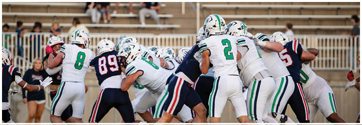 A football game is taking place on a field with players wearing blue and white uniforms. Description generated by AI