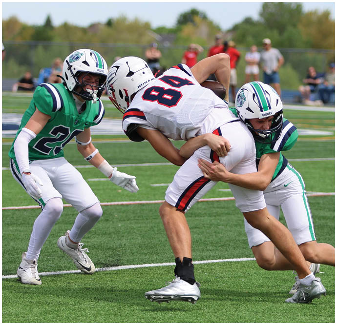 Three football players in blue and white uniforms running on a field. Description generated by AI
