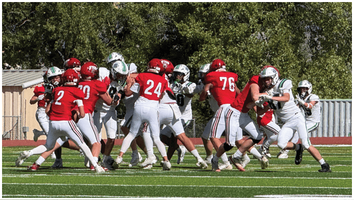 Three football players in blue and white uniforms running on a field. Description generated by AI