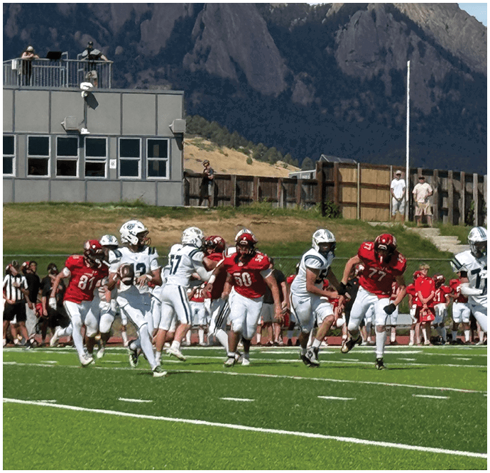 Three football players in blue and white uniforms running on a field. Description generated by AI