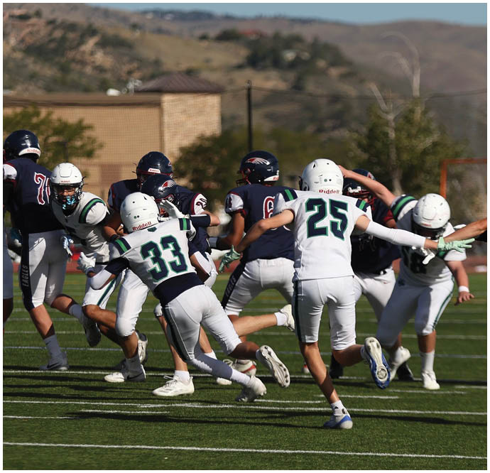 Three football players in blue and white uniforms running on a field. Description generated by AI
