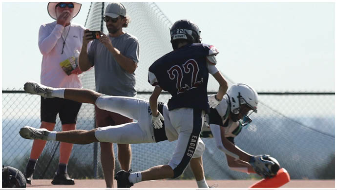 Three football players in blue and white uniforms running on a field. Description generated by AI