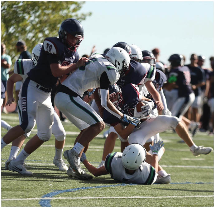 Three football players in blue and white uniforms running on a field. Description generated by AI