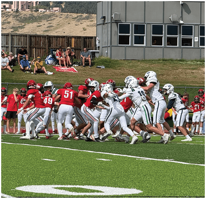 Three football players in blue and white uniforms running on a field. Description generated by AI