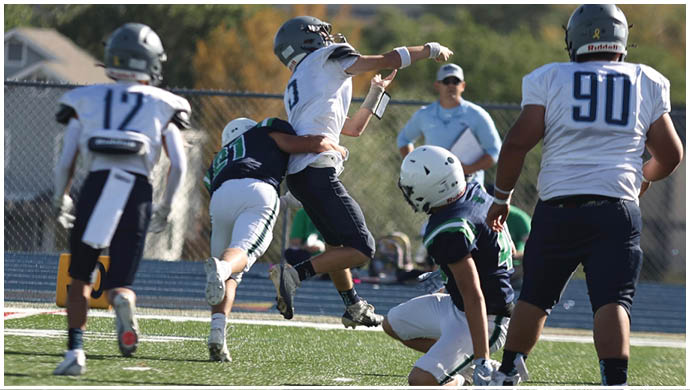 Three football players in blue and white uniforms running on a field. Description generated by AI