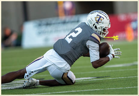 A football player wearing a black jersey with the number 11 on it. Description generated by AI