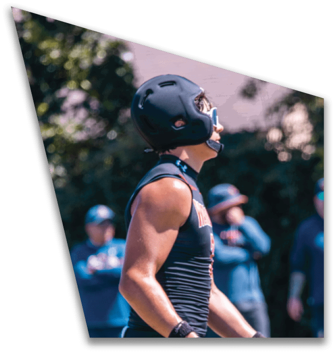 Two people in black football uniforms are engaged in a handoff with a football on a green field. Description generated by AI