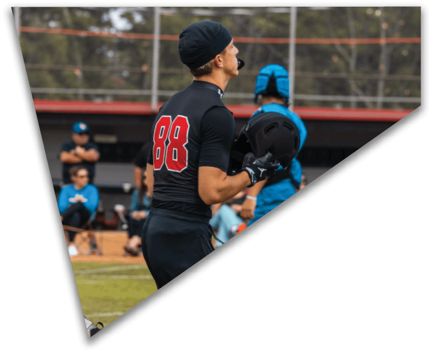 A group of football players in black uniforms are lined up on the field preparing for a play while players in white uniforms stand in the background. Description generated by AI