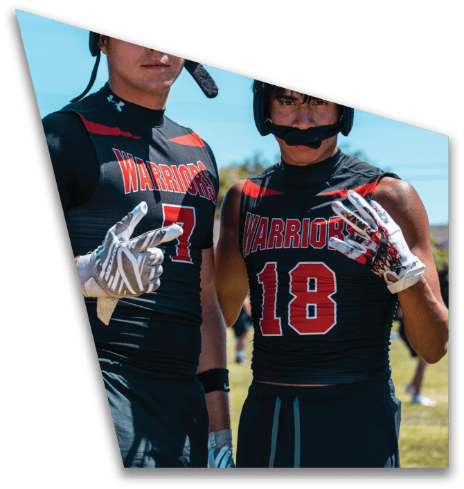 Two people in black football uniforms are engaged in a handoff with a football on a green field. Description generated by AI