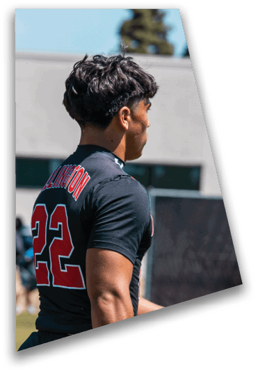A group of football players in black uniforms and helmets are huddled together on a field during a game. Description generated by AI